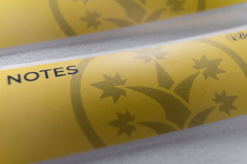 Macro shot of BudTrainer yellow sticky notes with cannabis grow logo and notes section.